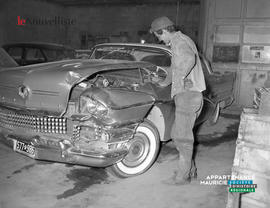 001 - Un homme regarde à l'intérieur d'une voiture accidentée.